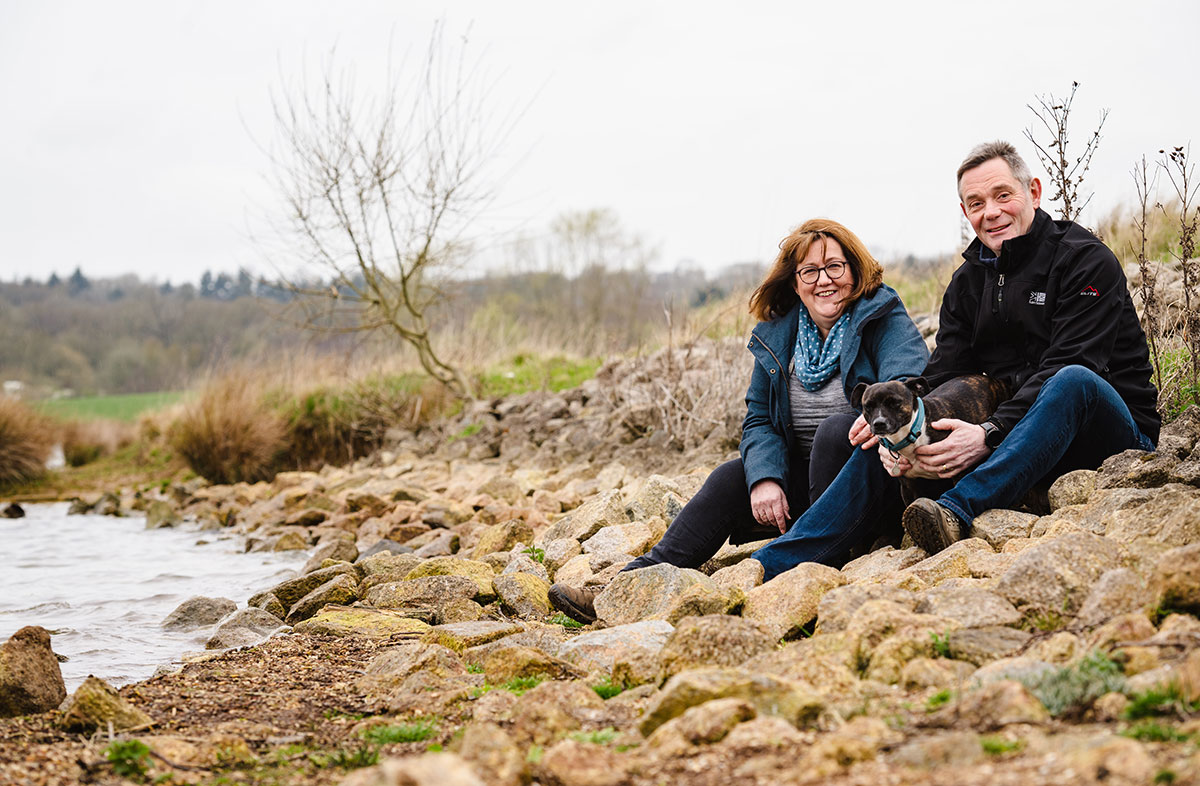 Rupert and Angela sit by Rutland Water with their small dog