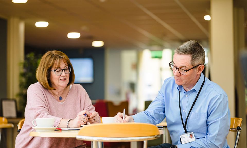 Angela and Rupert sit at table writing notes